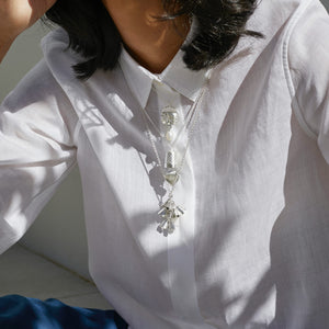 Close up of woman wearing white shirt with layers of silver necklaces