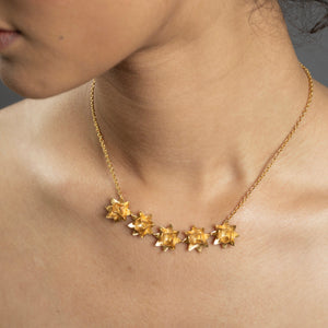 close up gold five lotus necklace on woman