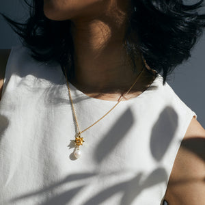 Lotus Pearl necklace in gold on woman wearing cream top