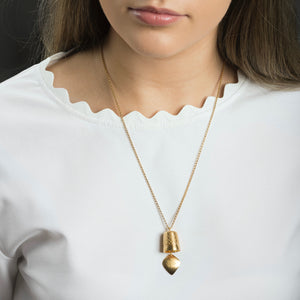 woman wearing gold precious bell pendant 
