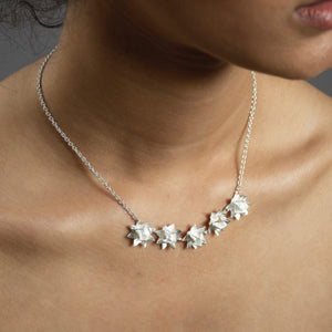 Close up of silver five lotus necklace on model