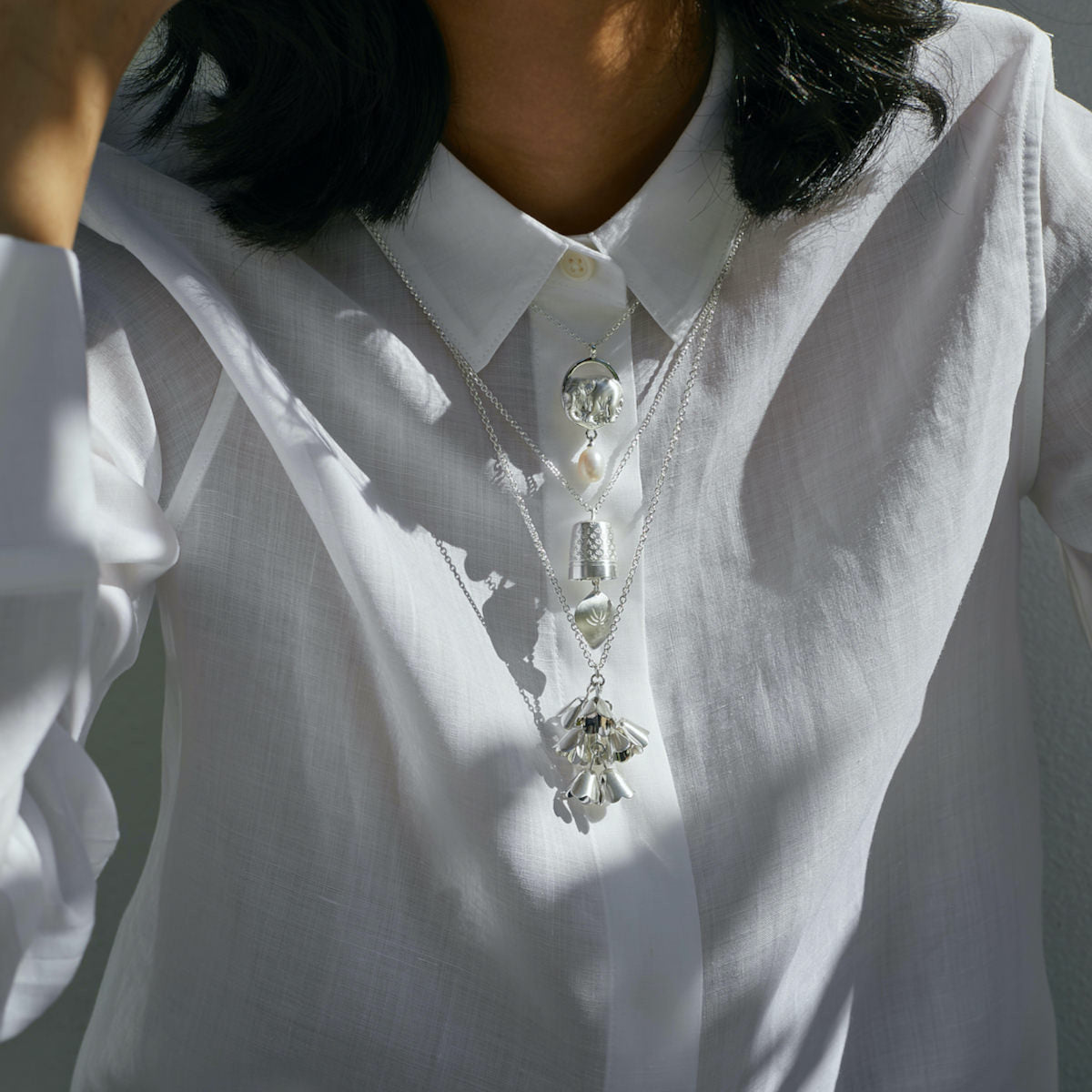 Brave Edith Precious and Padauk silver necklaces worn layered over a white shirt