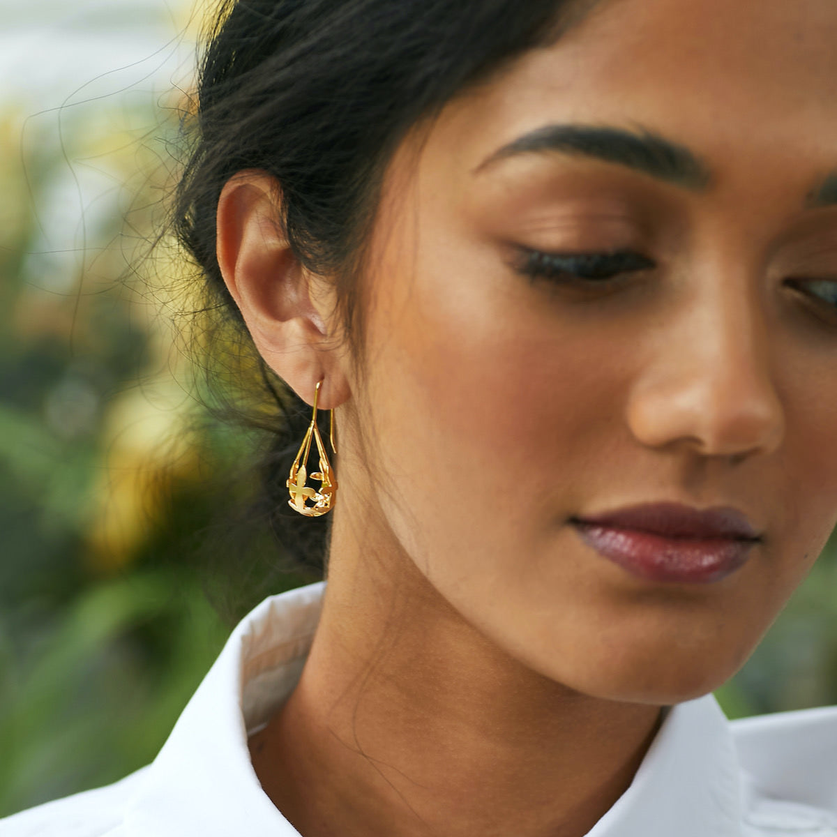 Thoughtful woman wearing Brave Edith Gold Thanaka Leaf Drop earrings
