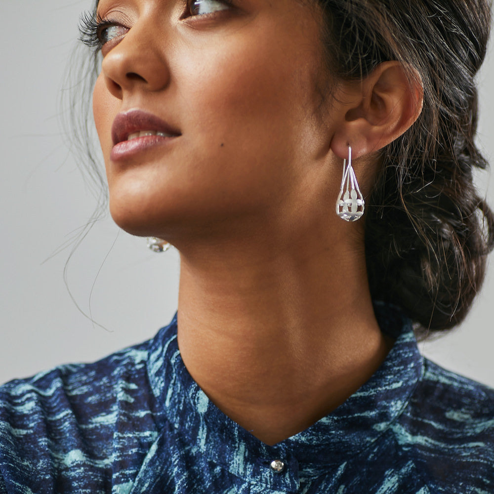 Woman thoughtfully looking into the distance wearing Brave Edith Thanaka Leaf Drop Earrings in silver