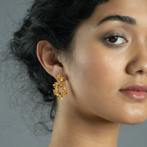close up on woman wearing gold lotus wreath earrings 