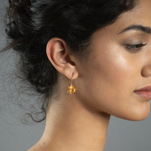 close up of woman wearing gold lotus hook earrings