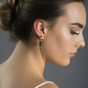 close up of woman wearing gold lotus earrings with Tahitian pearl 
