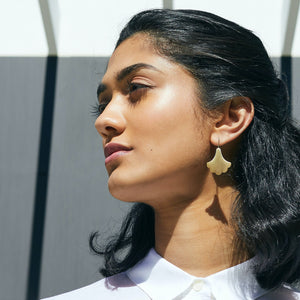 Woman wearing gold plume hook earrings looking to the side