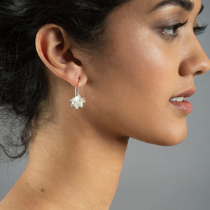 close up of woman wearing silver lotus hook earrings