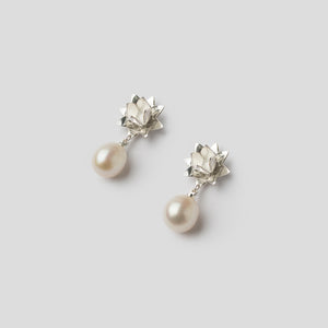 silver lotus pearl earrings on angle on white background