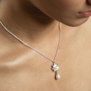 close up of woman wearing silver lotus pearl necklace
