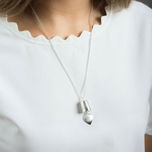 woman wearing silver precious bell pendant 